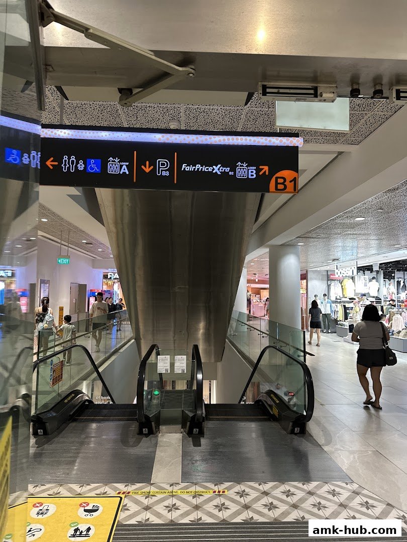 Escalators in a shopping mall with directional signage for FairPrice Xtra.