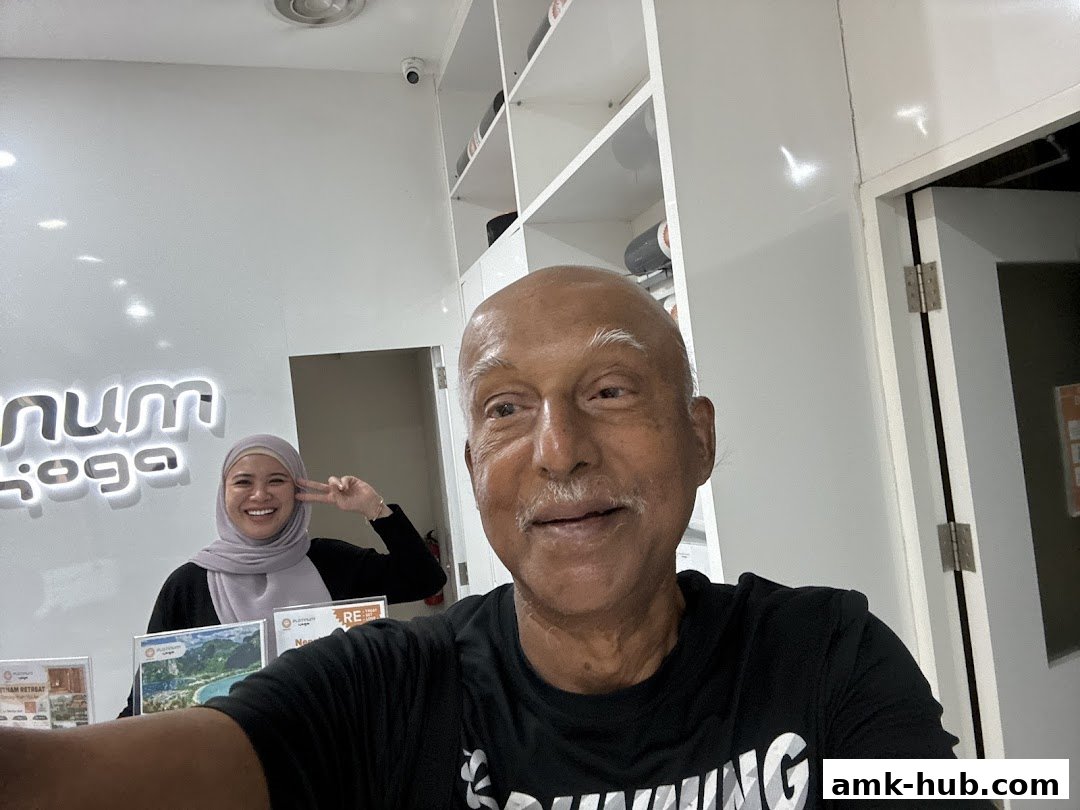 A man takes a selfie with a smiling woman in the background at Platinum Yoga.