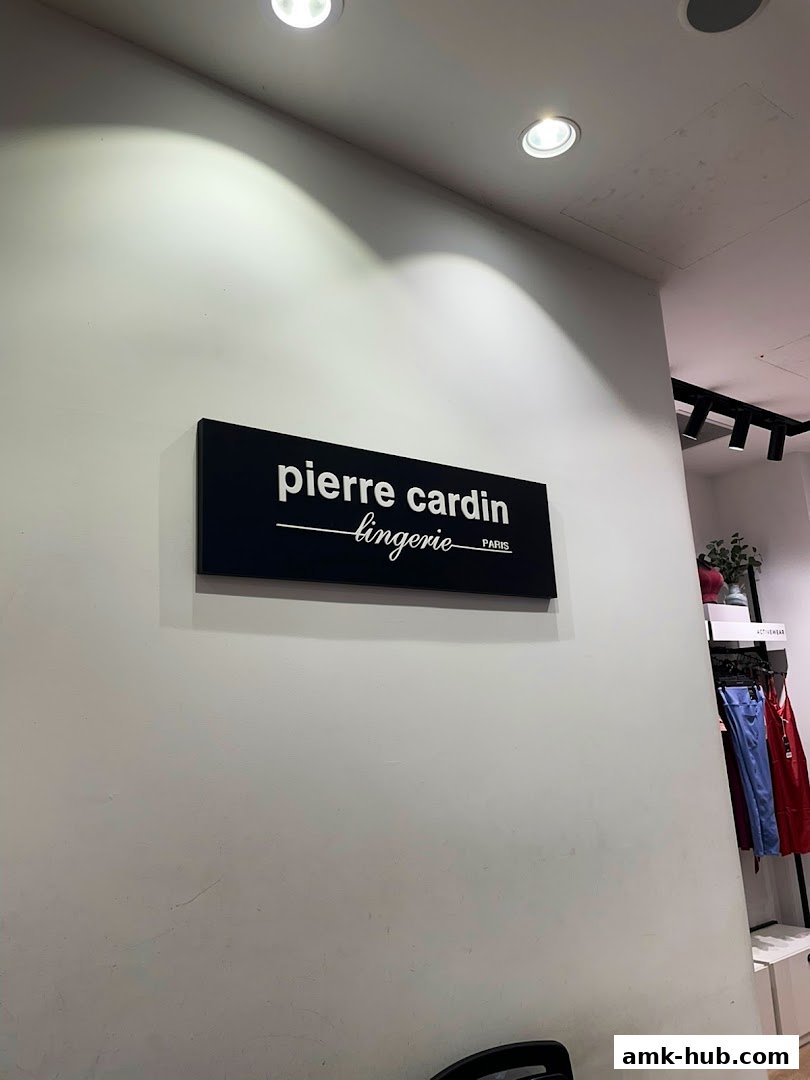 A sign for Pierre Cardin Lingerie with clothing displayed on racks in the background.