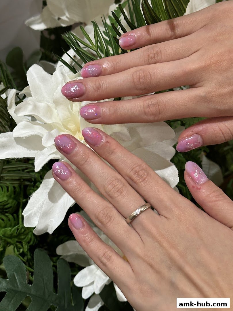 Close-up of hands with beautiful pink and purple gradient nails adorned with glitter.