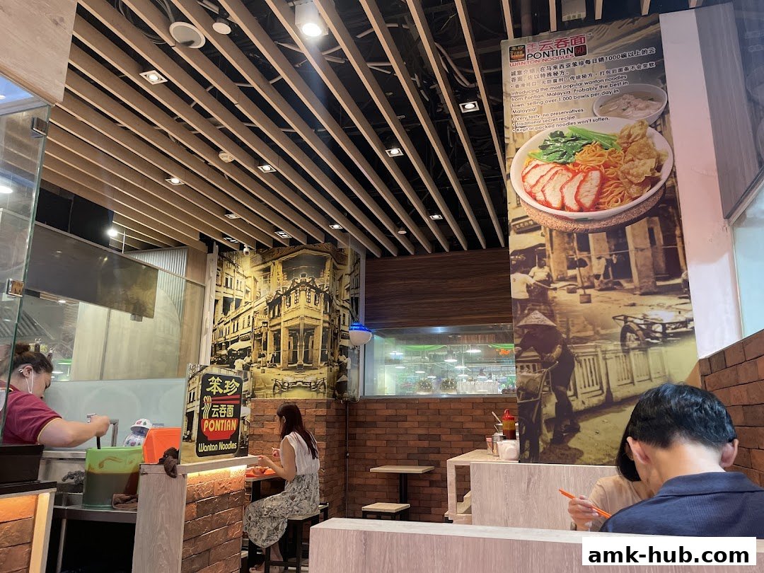 Interior of Pontian Wanton Noodles shop with customers and a large promotional poster.
