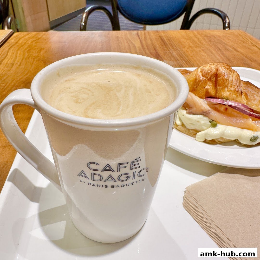 A close-up of a coffee mug and a salmon croissant on a table.