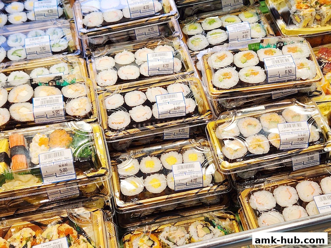A variety of pre-packaged sushi rolls and assorted Japanese dishes displayed in clear plastic containers.