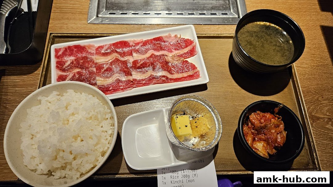 A meal set with raw beef slices, rice, kimchi, soup, and butter.