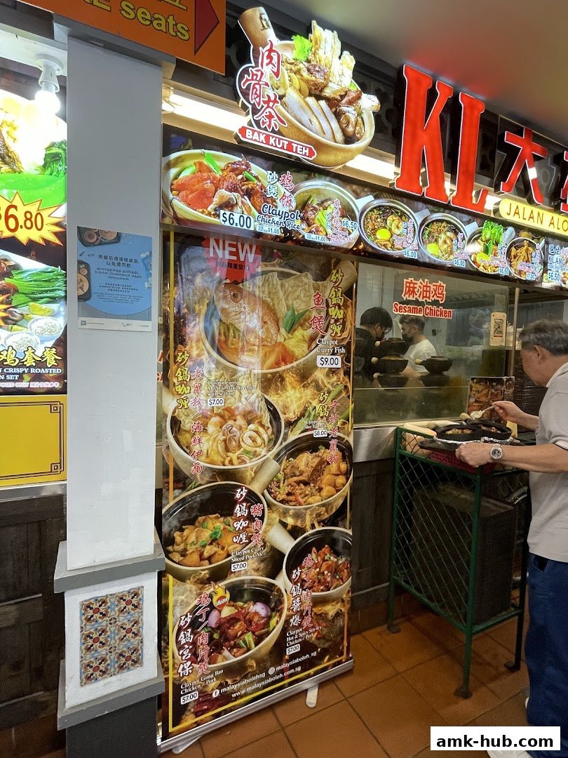 A food stall display featuring various Malaysian dishes like Bak Kut Teh and Claypot Curry.