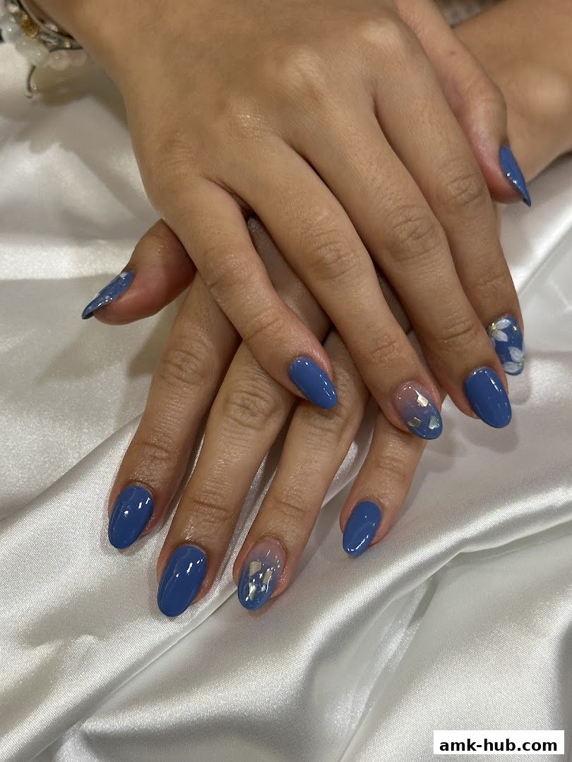 Close-up of hands with elegant blue gel nails, some with subtle glitter accents.