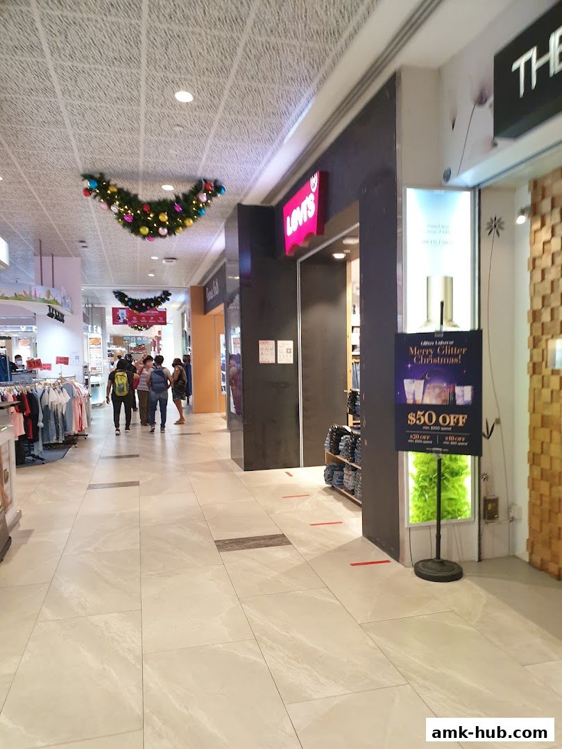 A shopping mall corridor with shops, including Levi's, and festive Christmas decorations.