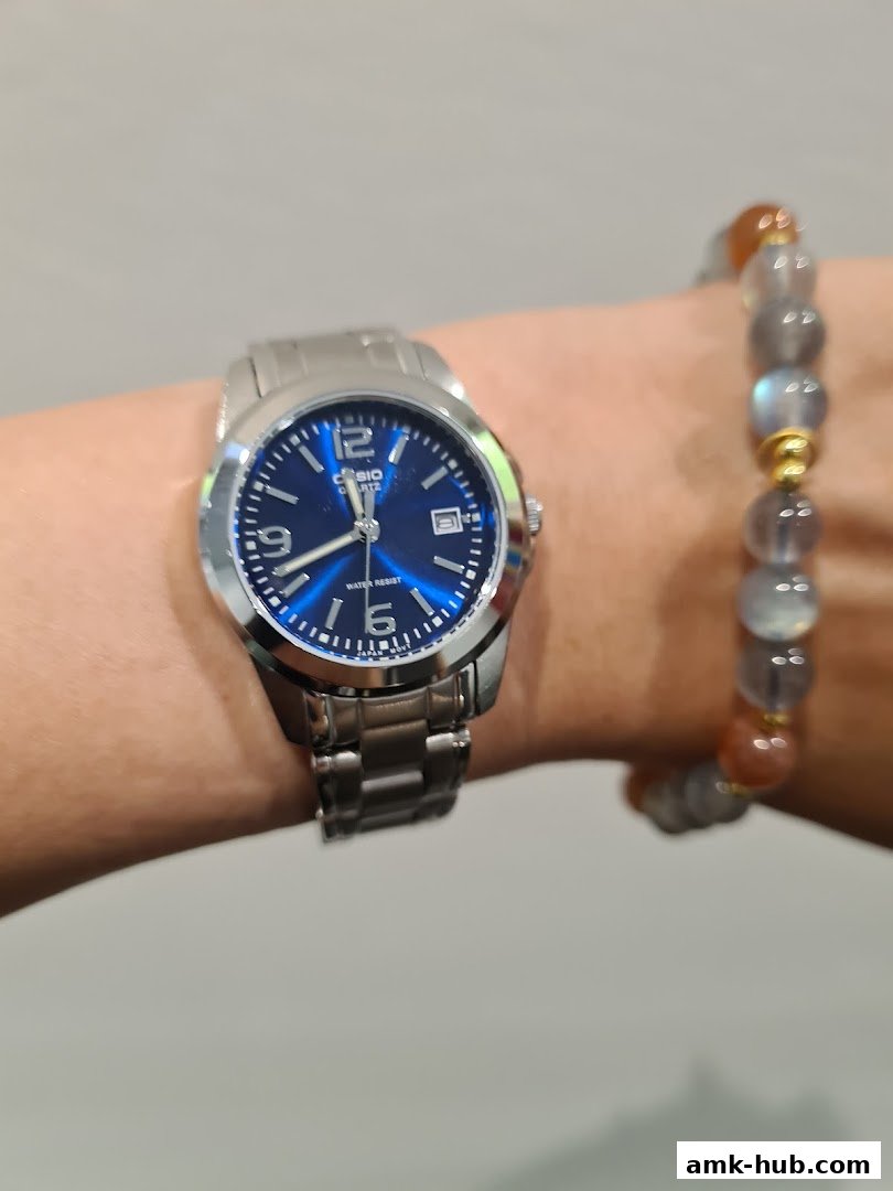 A close-up shot of a person's wrist wearing a silver Casio watch and a beaded bracelet.