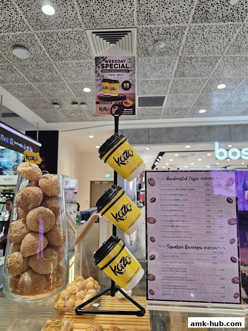 A display of pastries and coffee cups at a Kazo shop, with a menu board visible.