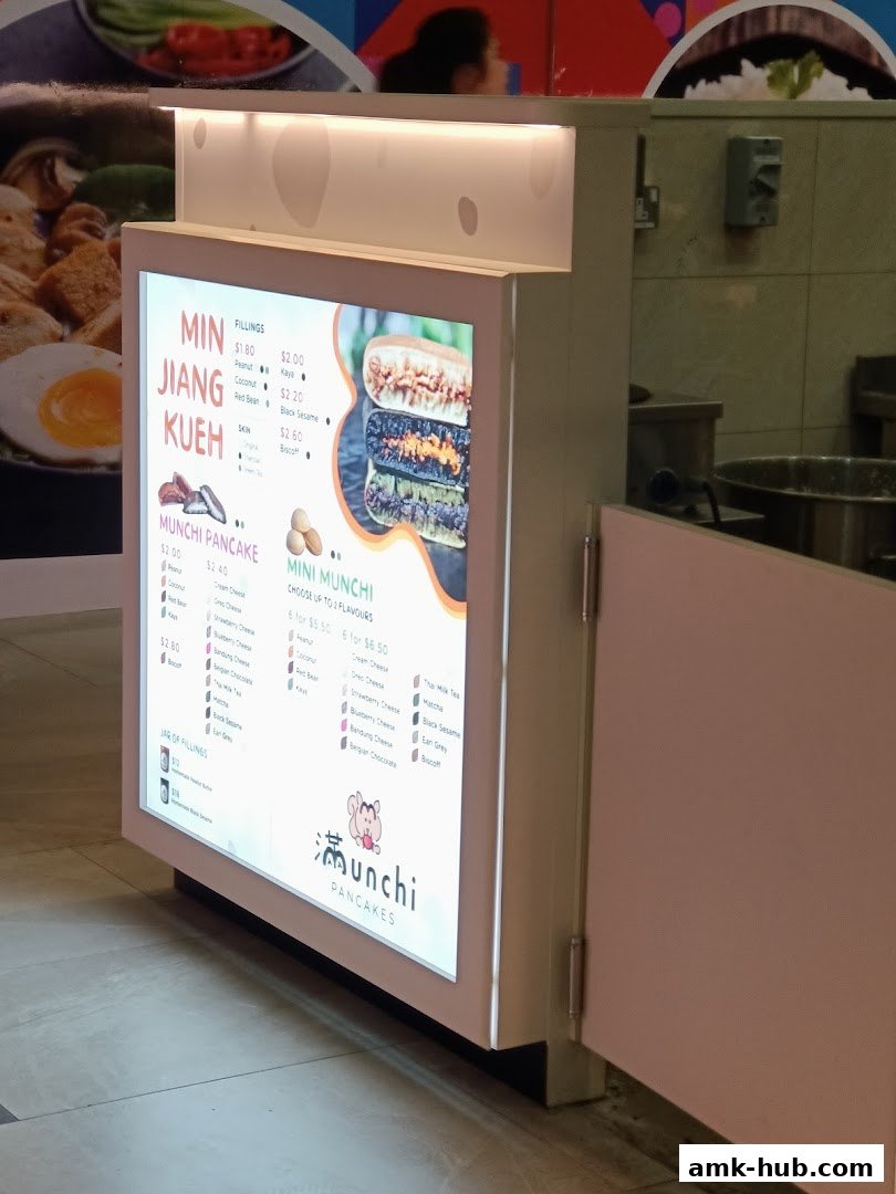 A brightly lit menu board for Munchi Pancakes, showcasing various pancake fillings and options.