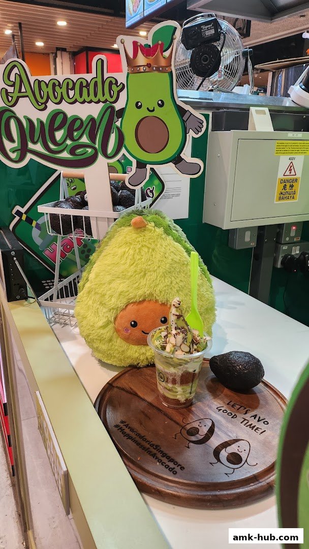 A display featuring an avocado-themed dessert, a plush avocado toy, and branding for Avocadoria.