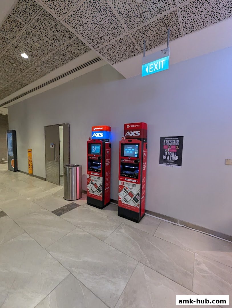 Two AXS payment kiosks are shown in a modern mall hallway with an exit sign overhead.