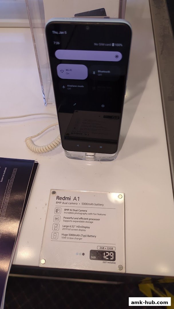 A Redmi A1 smartphone is displayed with its features and price on a white surface.