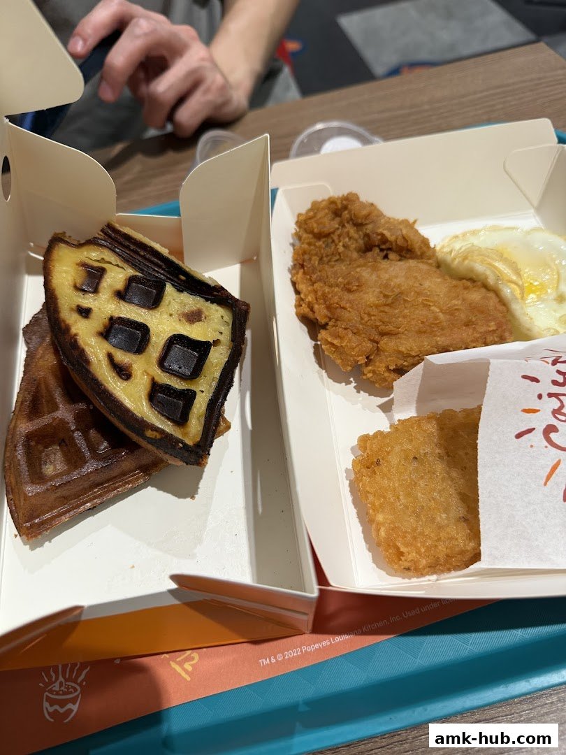 A close-up of Popeyes fried chicken, waffles, hash brown, and a fried egg.