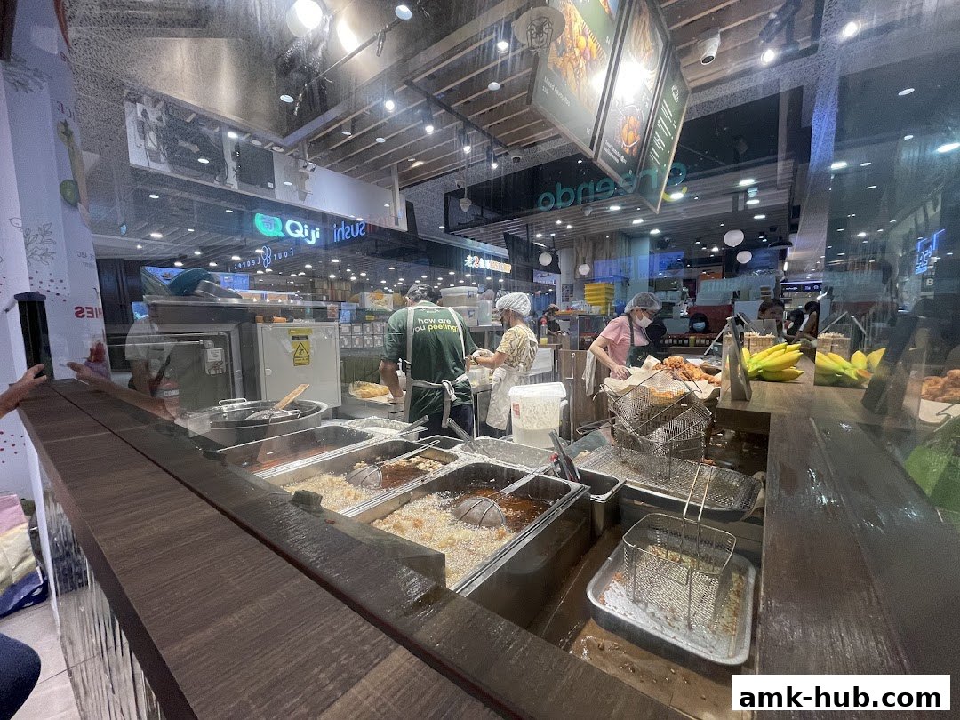 Staff preparing fried food behind a counter with deep fryers and baskets.