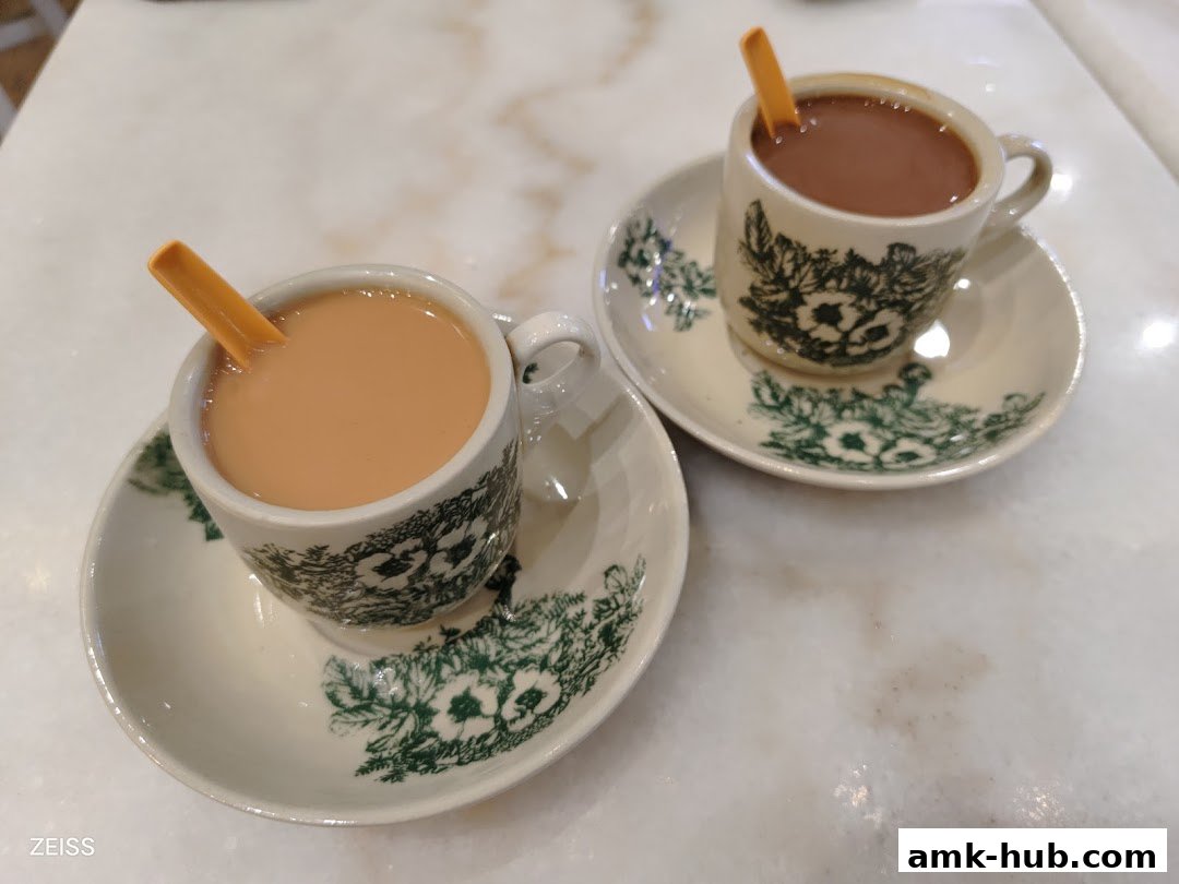Two cups of coffee with spoons on saucers, served at Heavenly Wang.