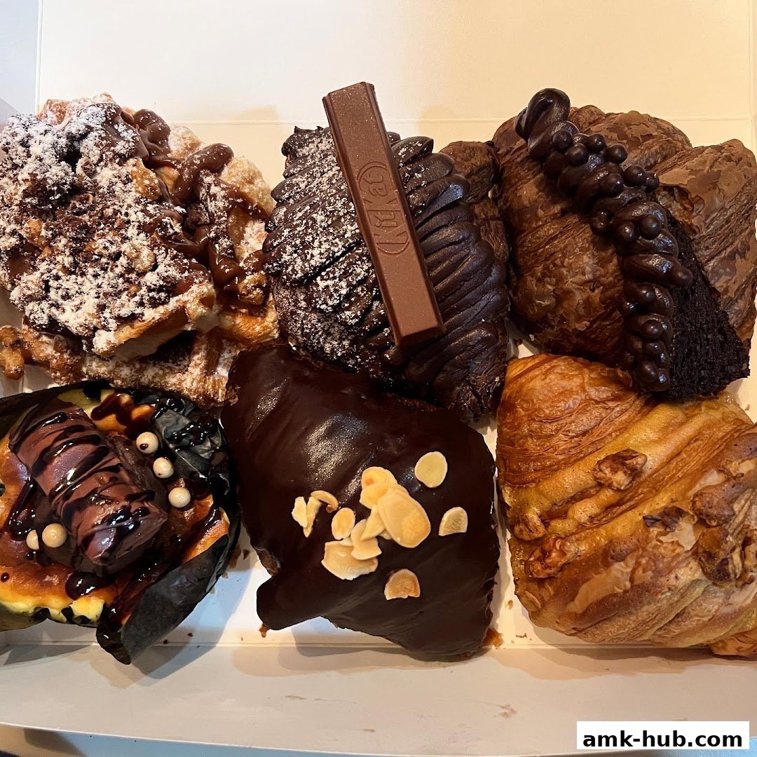 A box filled with assorted chocolate pastries and croissants, some dusted with powdered sugar.