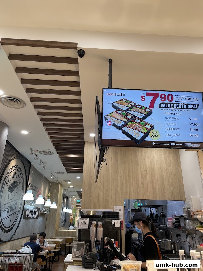 Interior view of a Umi Sushi restaurant with a digital menu board and staff at the counter.