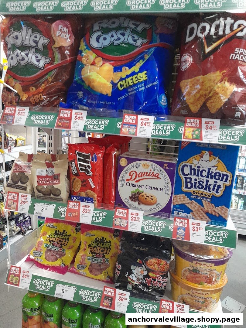 A well-stocked shelf inside 7-Eleven featuring a variety of snacks, instant noodles, and drinks.