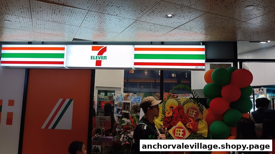 The brightly lit entrance of a 7-Eleven convenience store, adorned with festive balloons and floral arrangements.