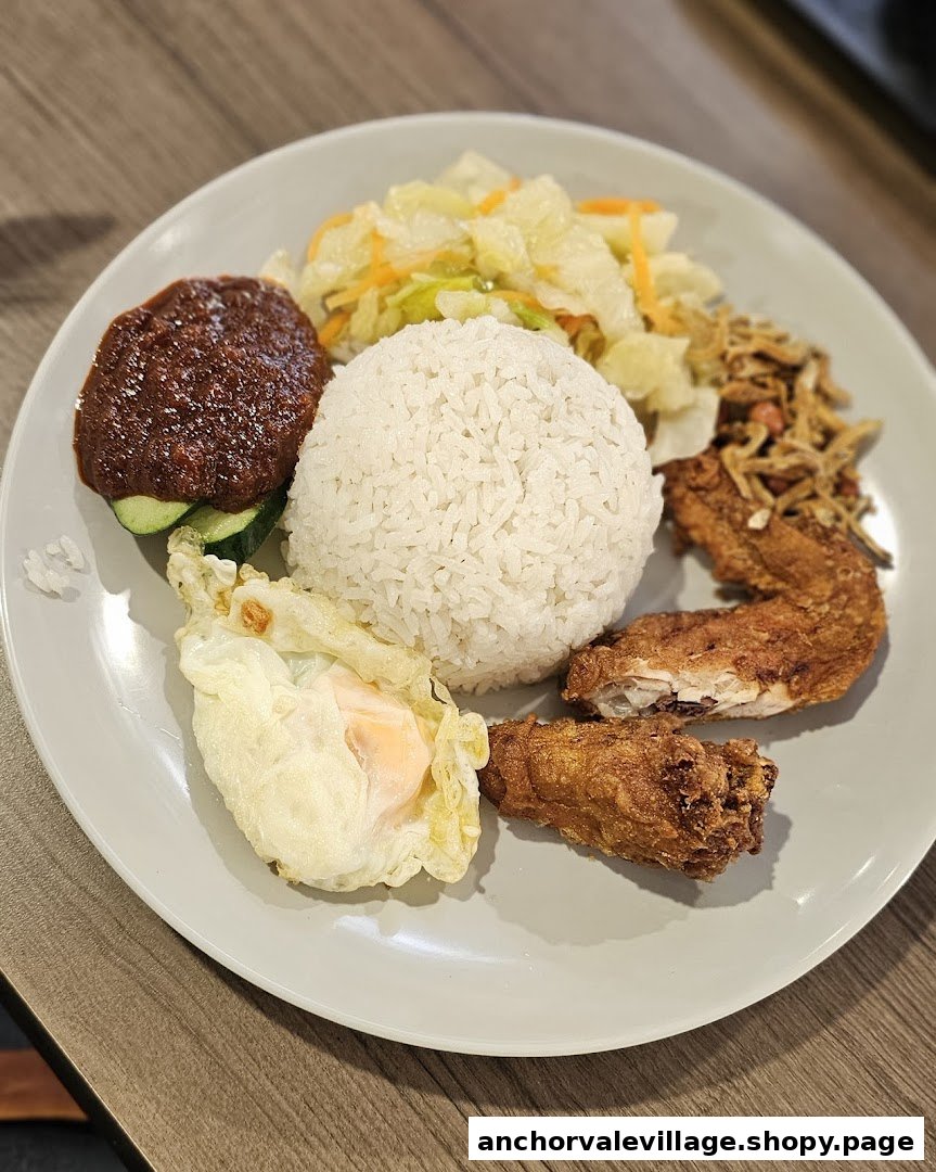 A delicious plate of Nasi Lemak featuring fragrant rice, fried chicken, egg, sambal, and anchovies.