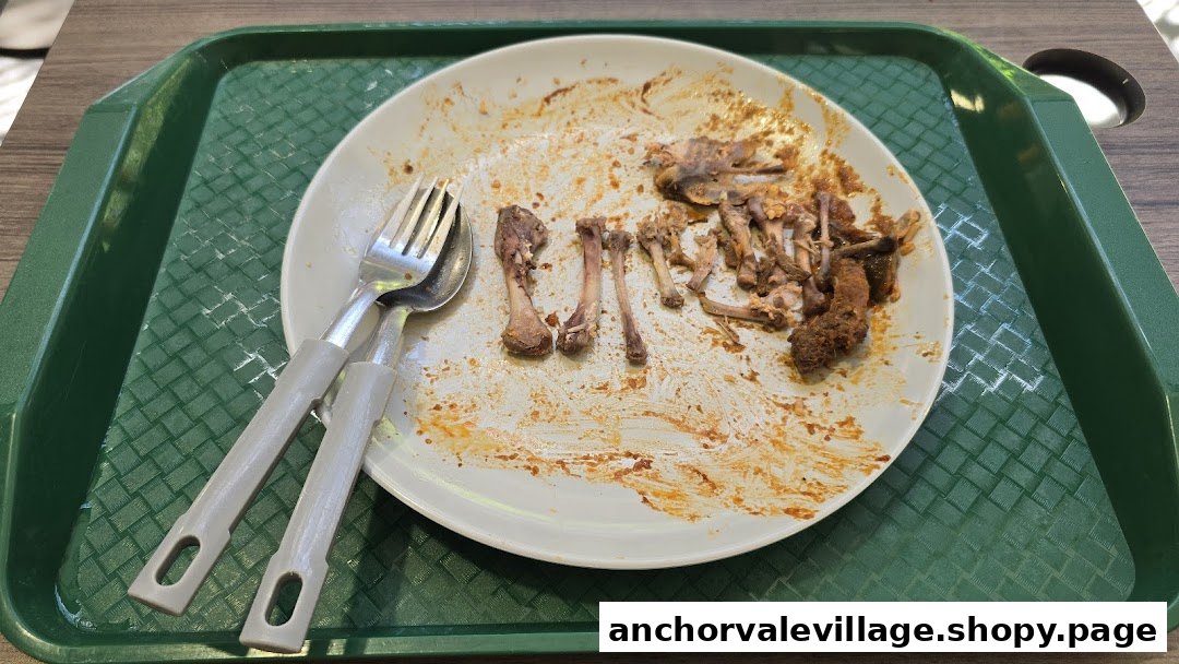 A white plate with chicken bones and cutlery on a green tray, showing a finished meal.