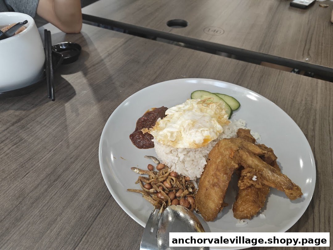 A delicious plate of Nasi Lemak with fried chicken wings, sunny-side-up egg, and sambal.