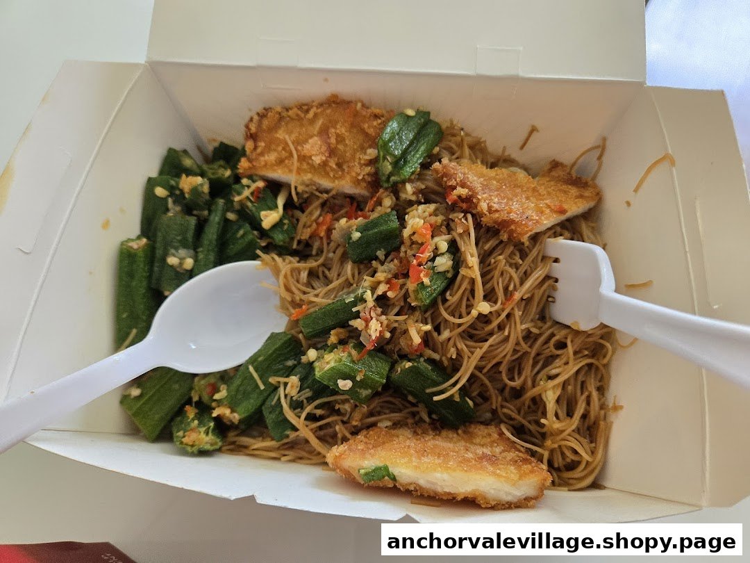 A takeaway box filled with fried noodles, crispy chicken cutlets, and okra, ready to eat.