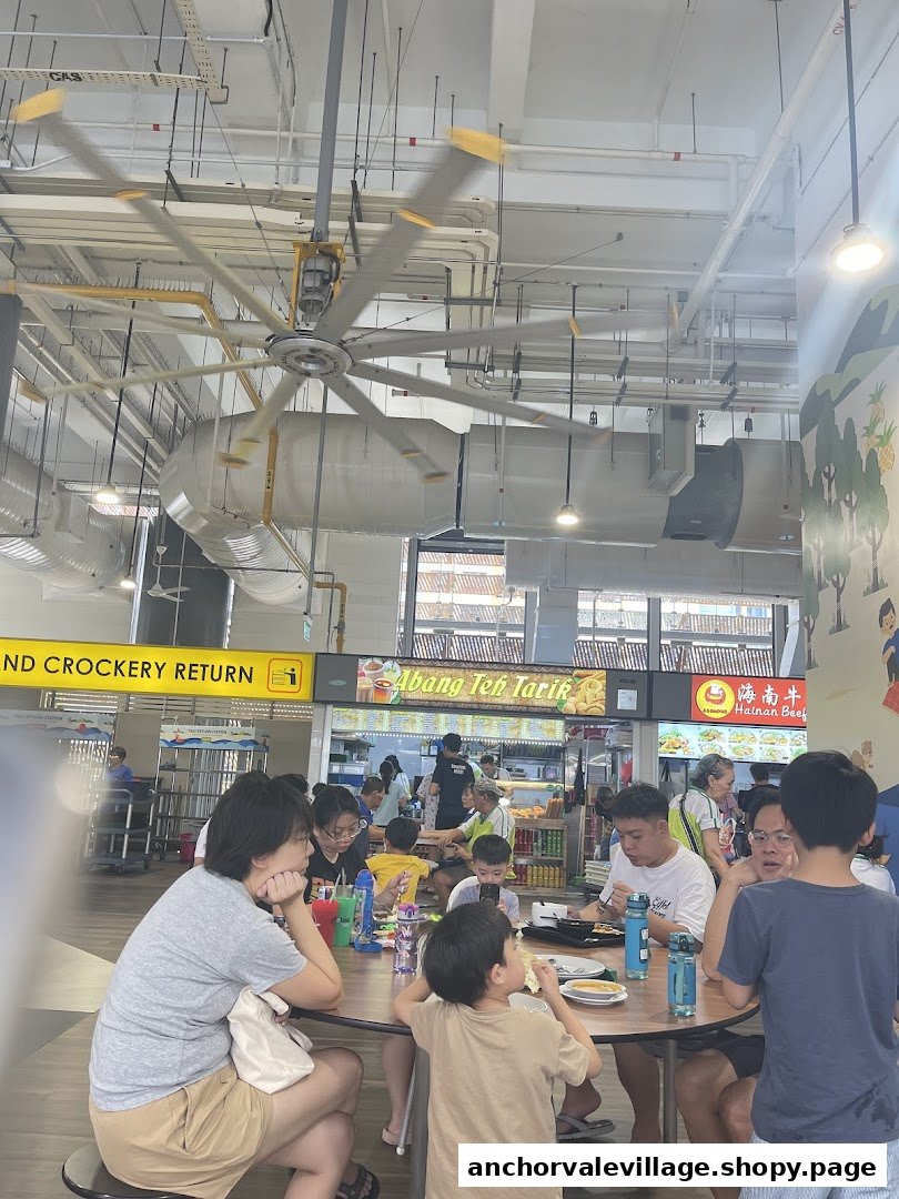 Diners enjoy meals in a bustling food court, with the 'Abang Teh Tarik' stall visible in the background.