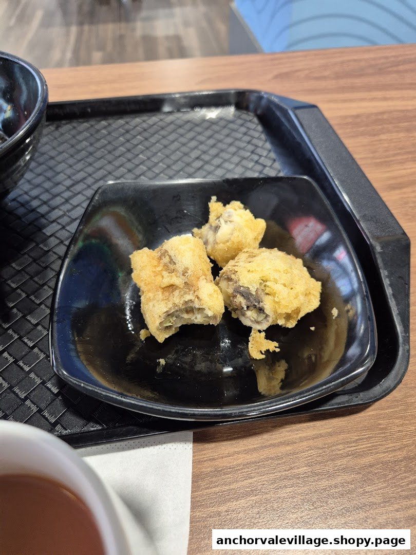 Close-up of golden-fried snacks on a black plate, served on a tray at Abang Teh Tarik.