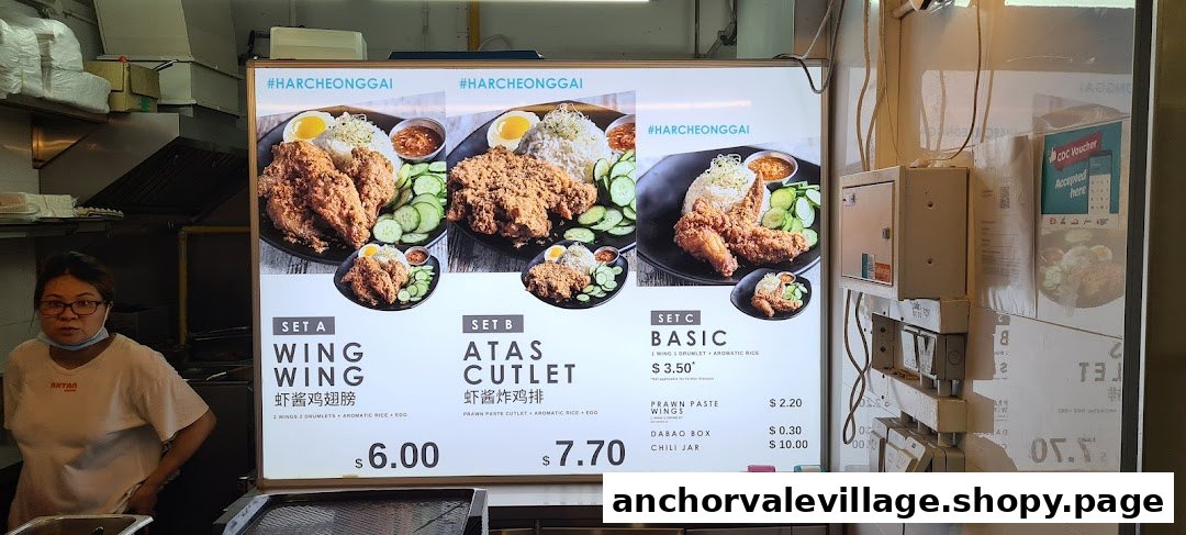 A staff member stands beside a brightly lit menu board displaying various fried chicken sets and prices.