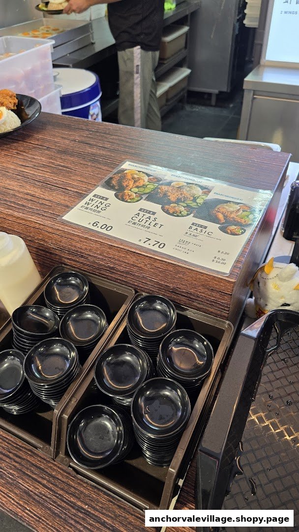 A close-up of a food stall counter displaying a menu with fried chicken sets and side dishes.
