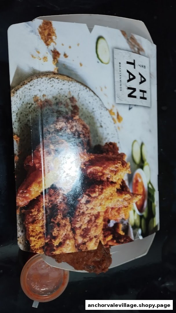 A box of crispy fried chicken wings from AH TAN WINGS with a side of dipping sauce.