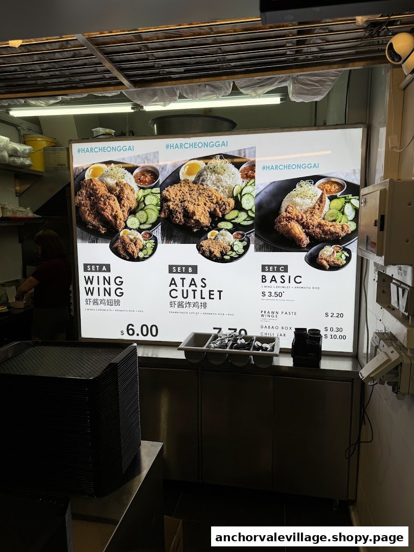 A brightly lit menu board showcasing various fried chicken and rice sets with prices at Ah Tan Wings.