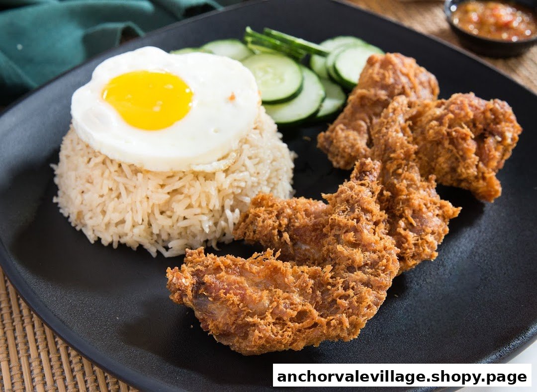 A plate of crispy fried chicken wings, fragrant rice, a sunny-side-up egg, and sliced cucumbers.