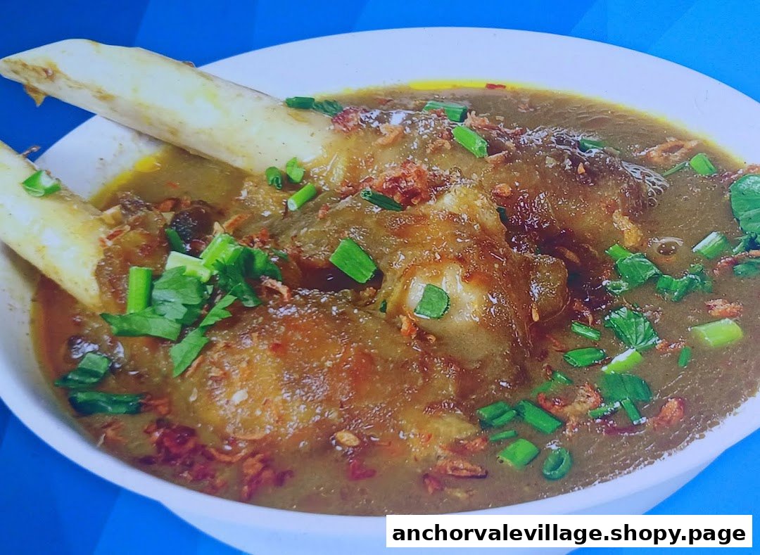 A close-up of a rich mutton soup with bones, garnished with green onions and fried shallots.