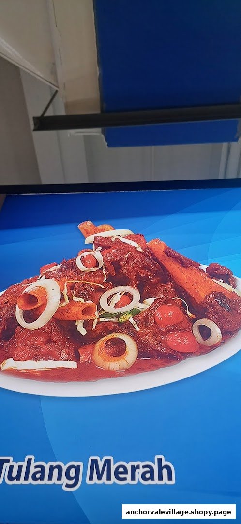 A vibrant plate of 'Tulang Merah' (red bones) stew, garnished with onions and tomatoes.