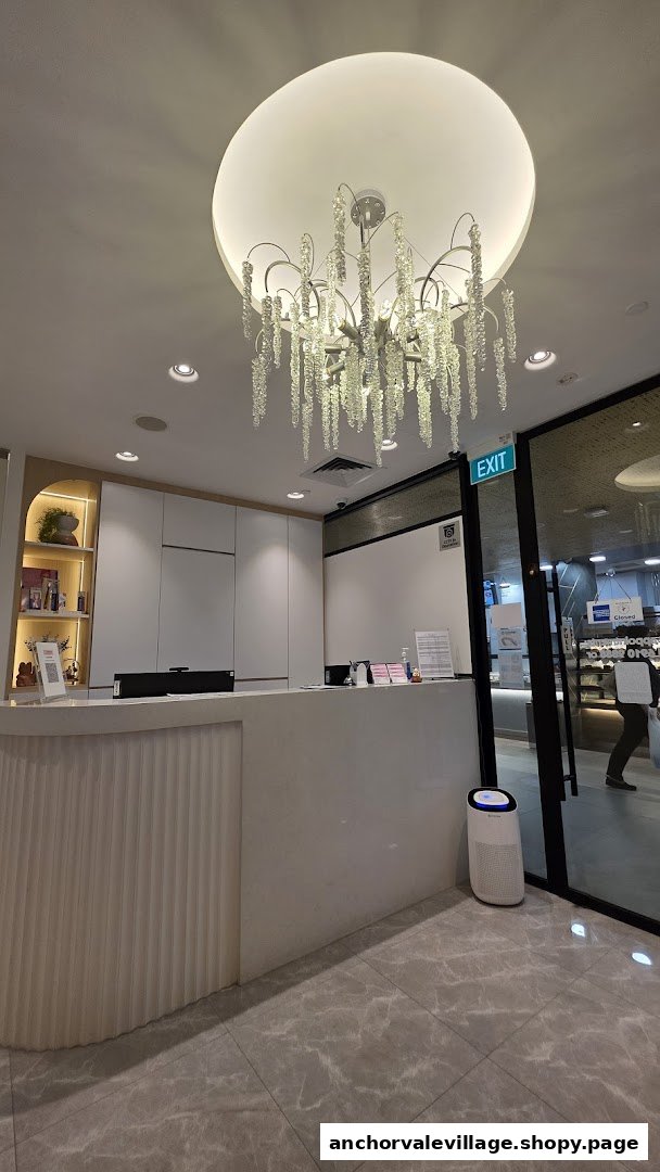 A modern and brightly lit reception area with a stylish chandelier and clean white desk.