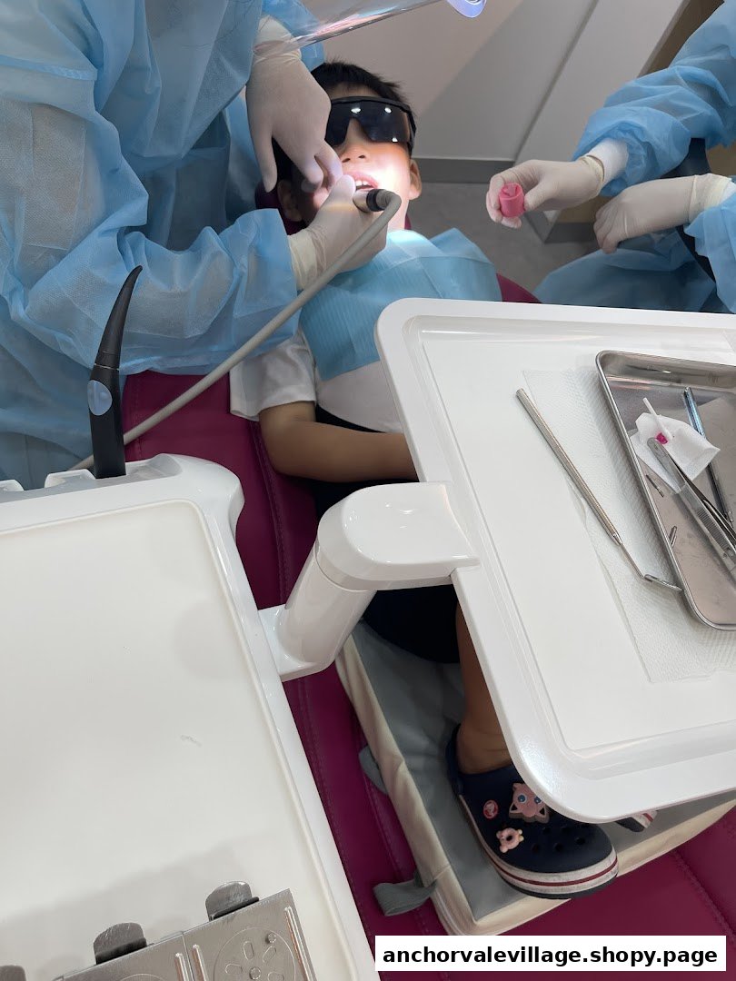 A young patient wearing protective glasses undergoing a dental procedure with staff in a modern clinic.