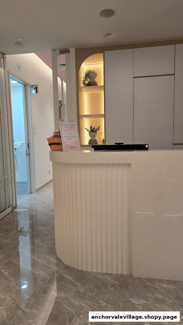 A clean and modern reception area with a curved desk and illuminated shelving at a dental clinic.