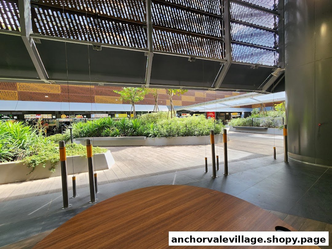 A spacious, modern hawker centre dining area with lush greenery and multiple food stalls in the background.