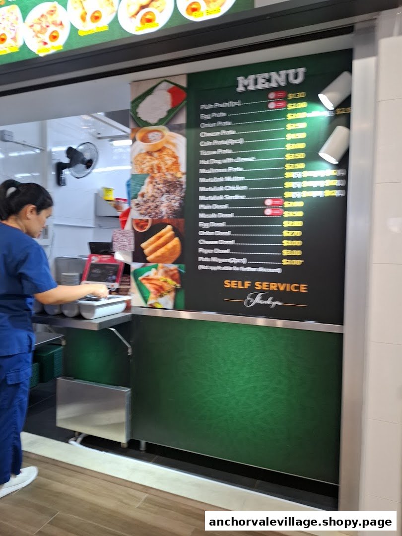 A hawker stall counter featuring a detailed menu board with various prata, murtabak, and dosai options.