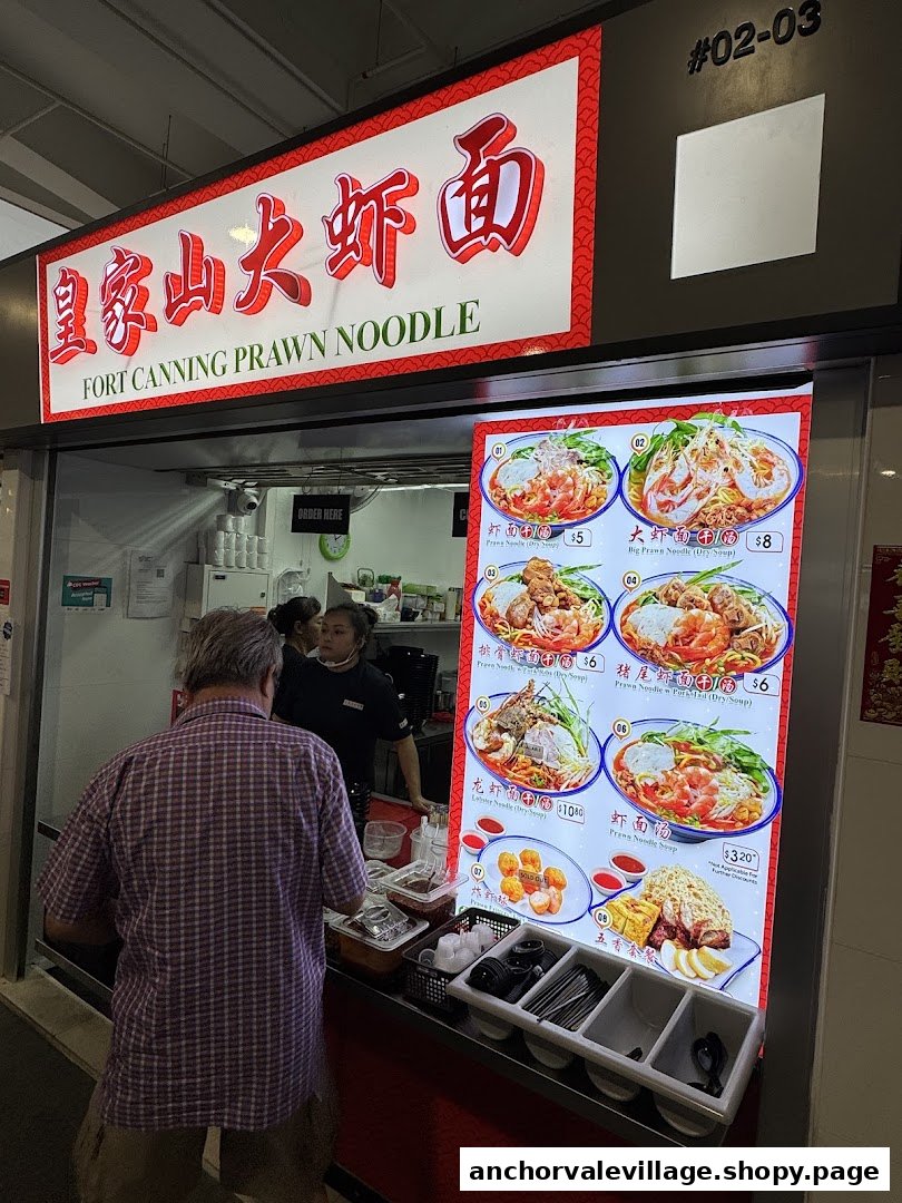 A customer orders at Fort Canning Prawn Noodle stall, featuring a vibrant menu board.