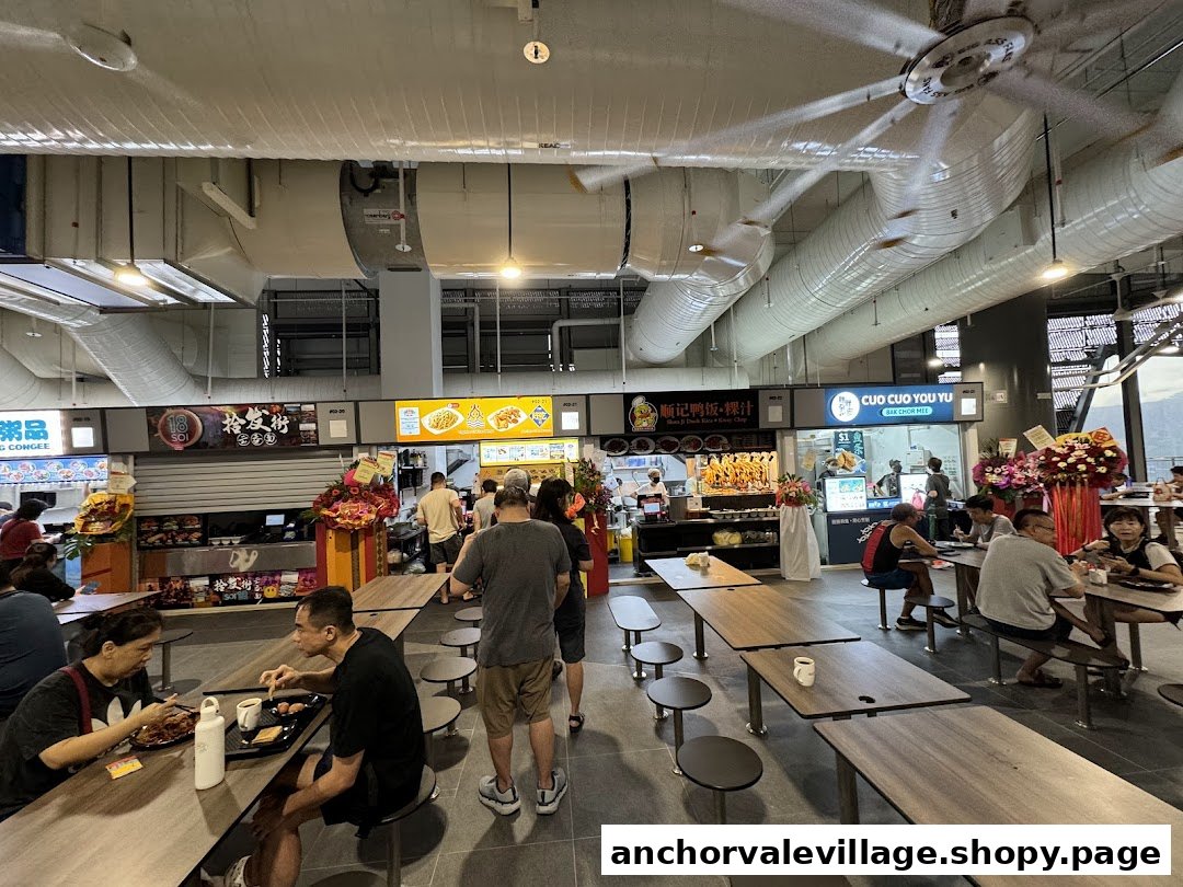 Diners enjoying meals at a bustling hawker centre with various food stalls.