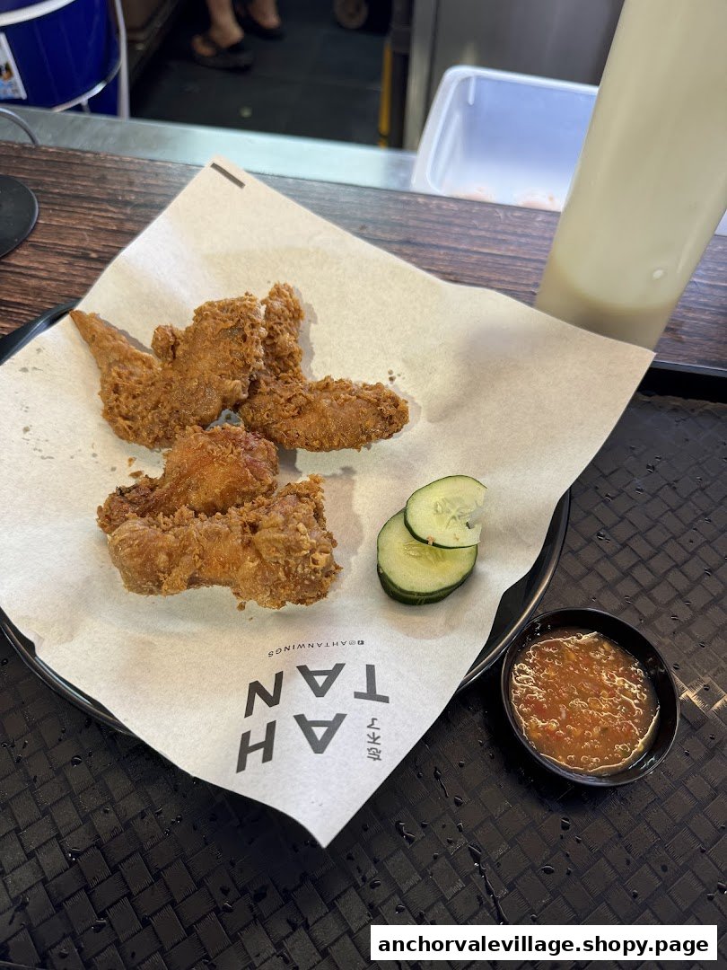Crispy fried chicken wings served with fresh cucumber slices and a side of chili sauce.