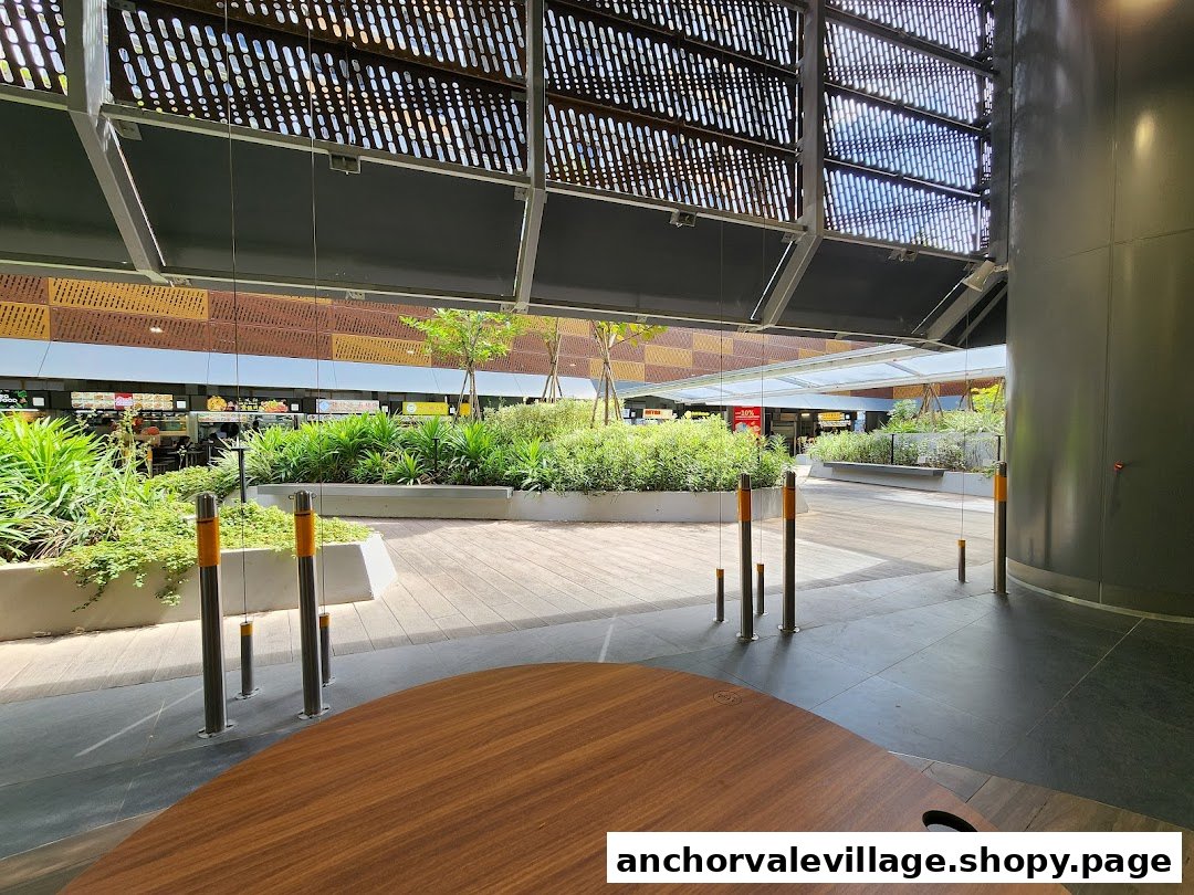 A spacious outdoor area with lush greenery and pathways leading to the Anchorvale Village Hawker Centre.