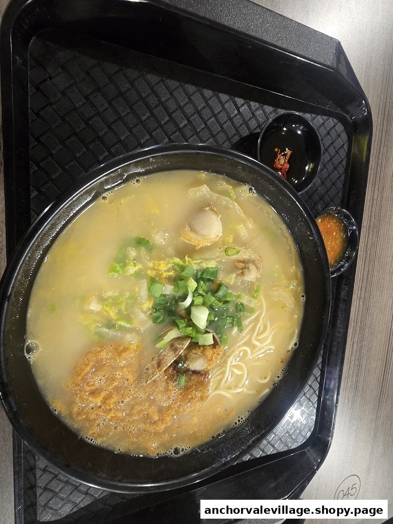 A close-up of a delicious bowl of ramen or ban mian with various toppings and broth.