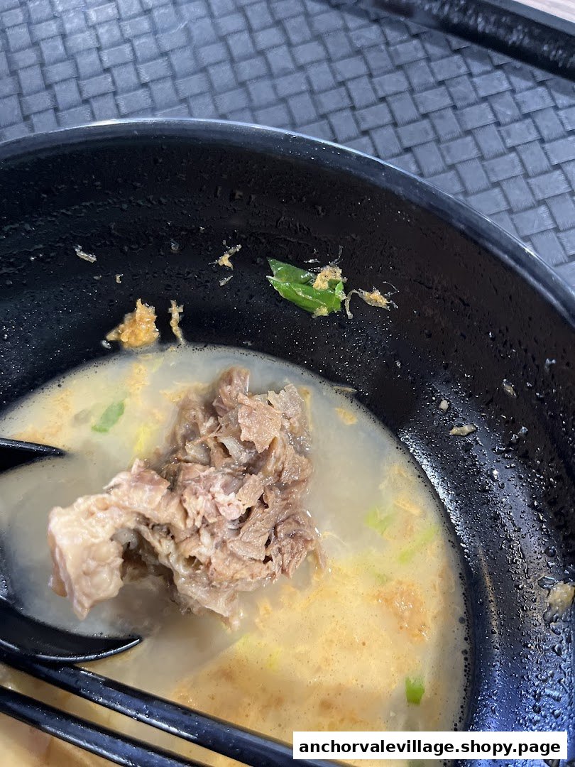 A close-up of a hearty bowl of ban mian or ramen with tender meat and rich broth.