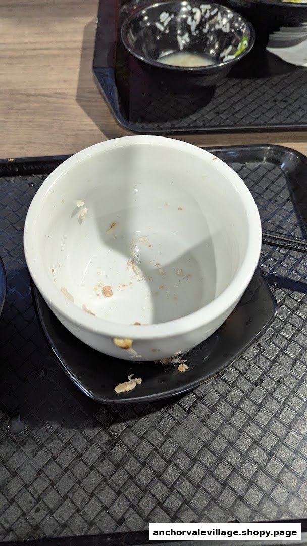 An empty white bowl and a partially eaten bowl on a black tray, indicating a finished meal.