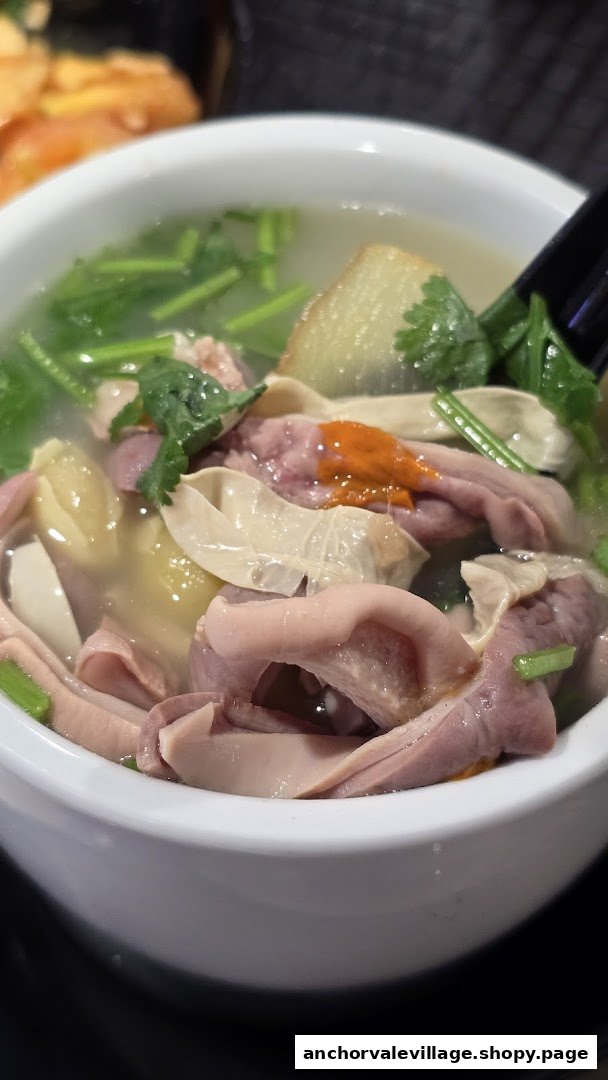 A close-up of a hearty bowl of traditional Chinese soup with intestines, vegetables, and a rich broth.